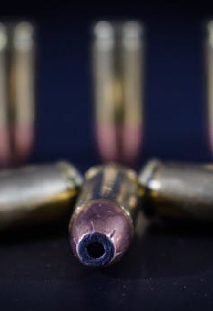 Detailed macro shot of handgun bullets lying on dark surface.