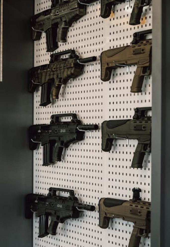 Collection of assault rifles mounted on a store display wall, showcasing various models.